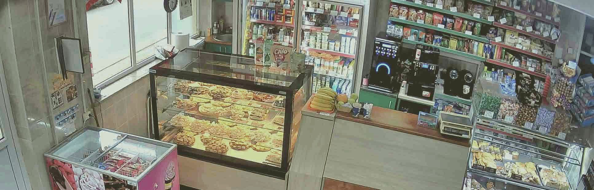Interiorul patiseriei: vitrina cu prăjituri, aparatul de cafea și rafturile din spatele tejghelei